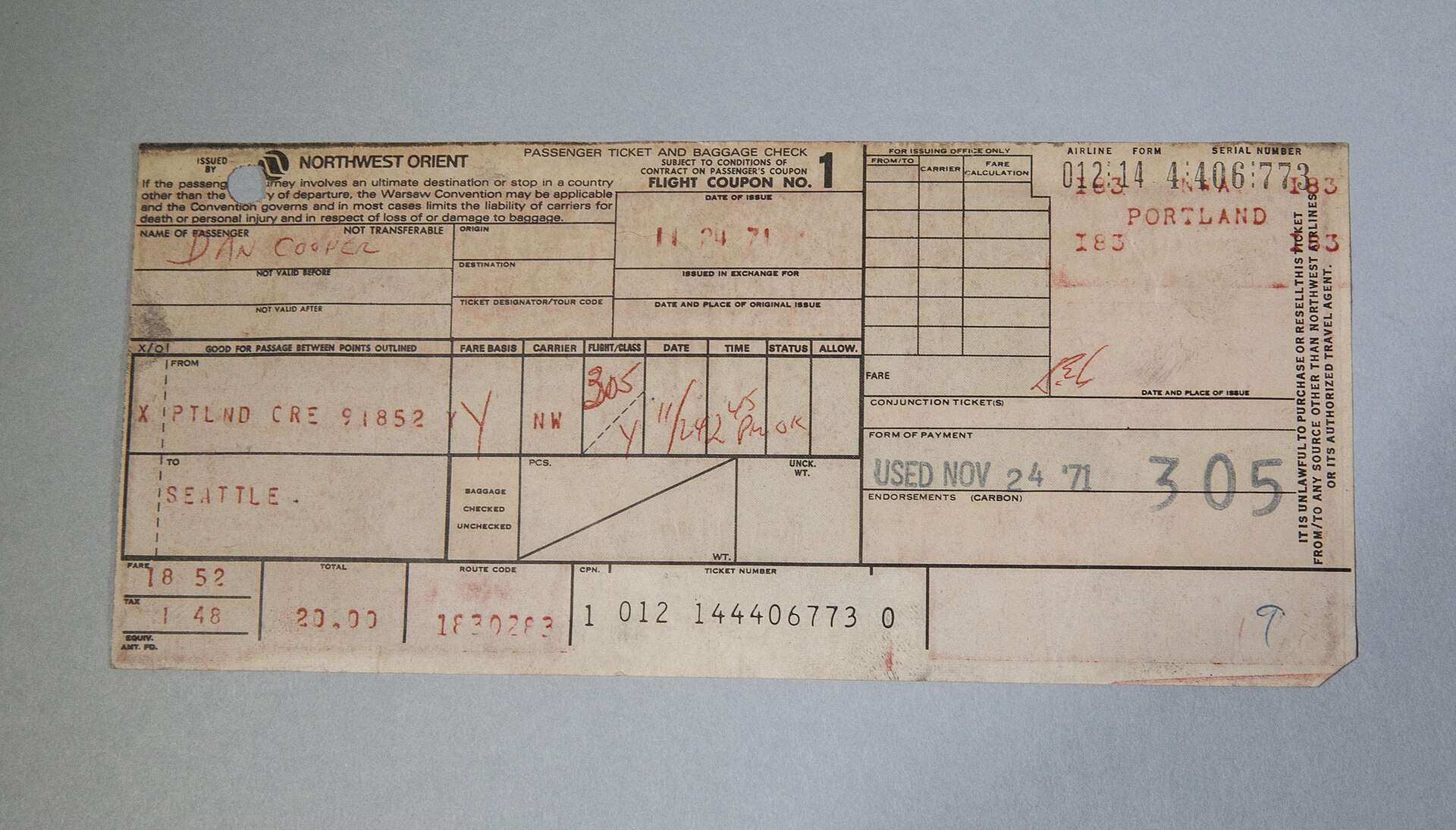 A worn 1971 Northwest Orient paper airline ticket, handwritten in red ink, showing the passenger name 'Dan Cooper,' the route from Portland to Seattle, flight 305, and a stamp reading 'USED NOV 24 '71.'